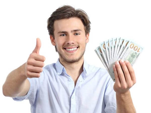 A man holds a bunch of money and gives a thumbs up. He is dead behind the eyes.