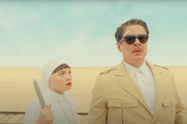 Still The Phoenician Scheme showing a man and a nun in the desert. The nun has a knife.