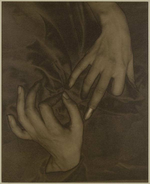 Sepia photograph of a woman's hands in fabric, with a thimble on one index finger