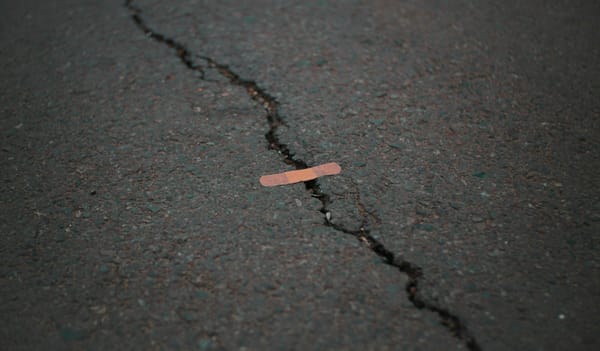 A crack in asphalt with a sticking plaster over it