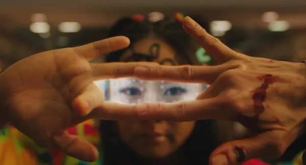 Bloodied hands form a window with their fingers through which they show an alternate universe Stephanie Hsu