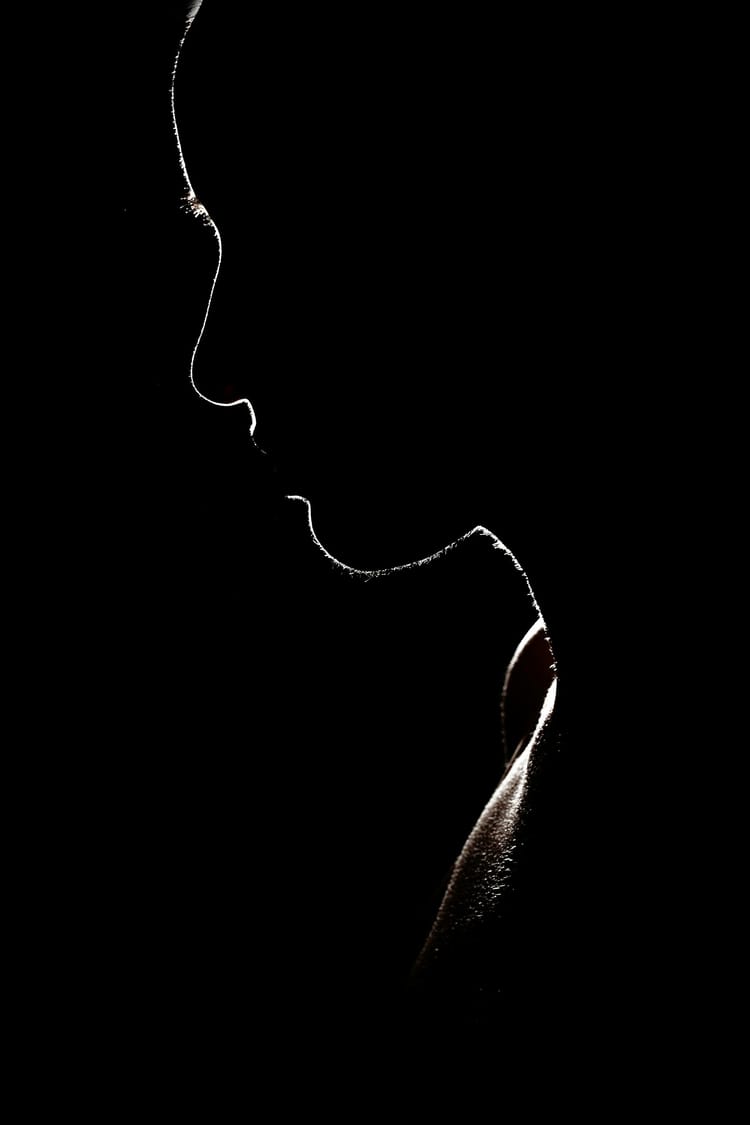 Backlit photo of a woman, with light behind creating an outline of her face